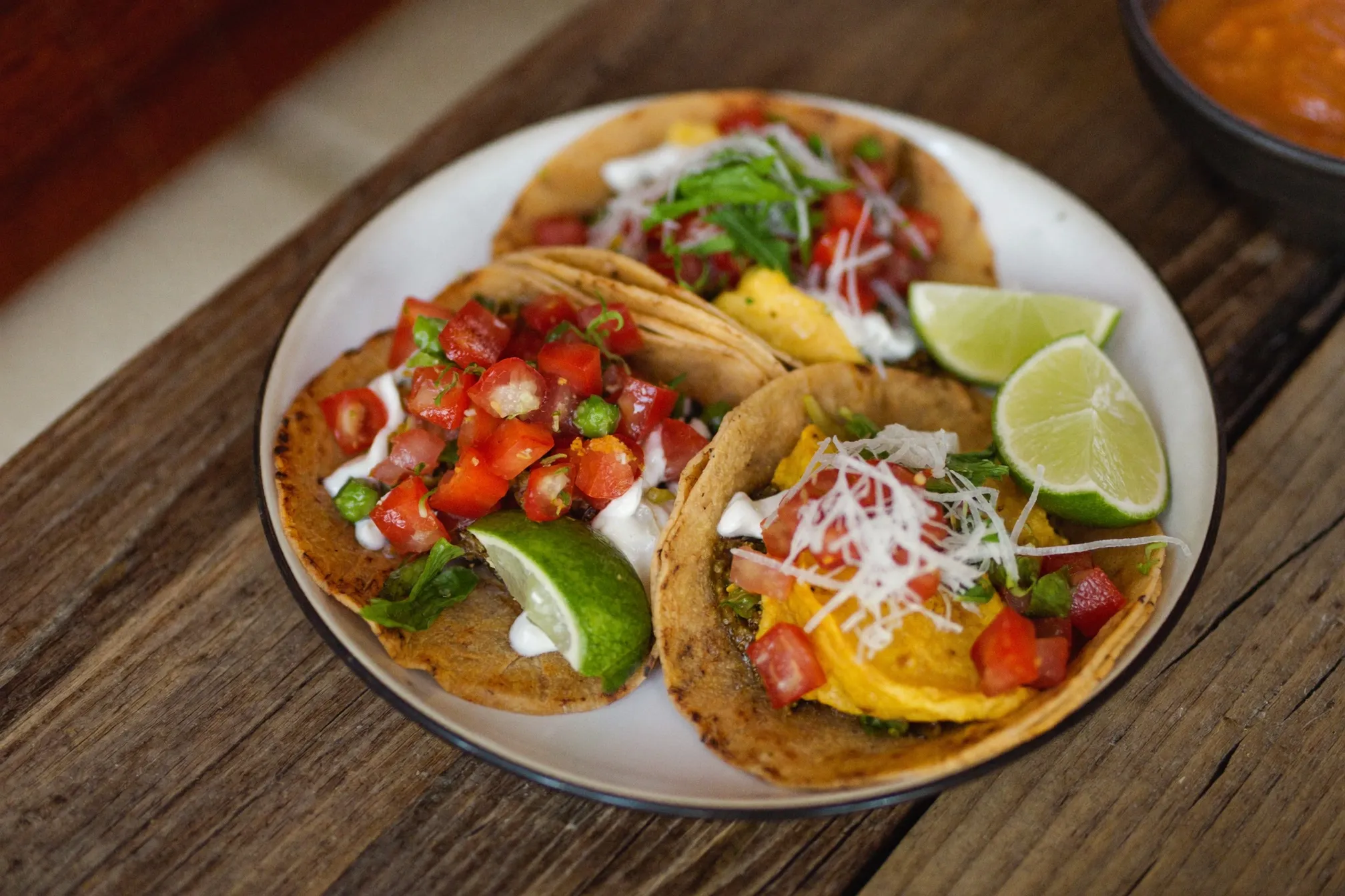 Plate of street tacos with lime and salsa in warm light